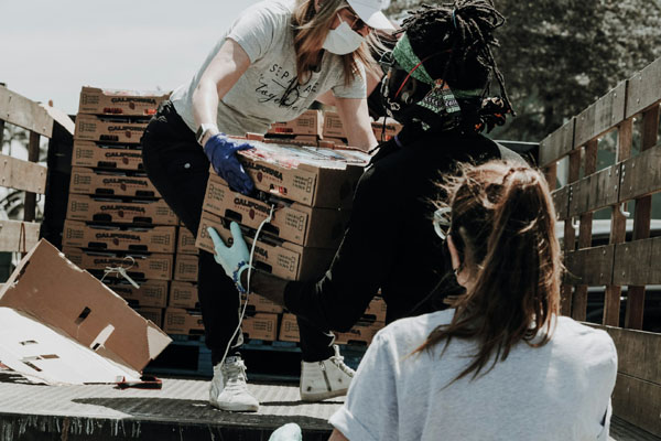  Three individuals are loading boxes onto a truck as part of their junk removal job.