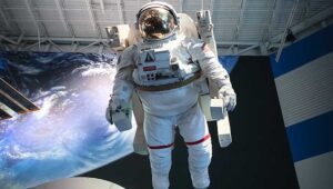 Astronaut floating in museum with distant planet in background.